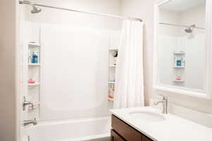 Bathroom featuring vanity and shower / bathtub combination with curtain