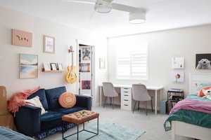 Bedroom with light colored carpet, an office area, and ceiling fan