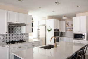 Kitchen featuring white cabinets, open shelves, built in appliances, light stone counters, and recessed lighting