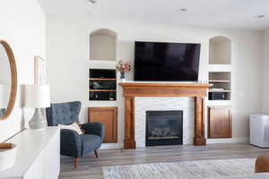 Living room with built in features, light wood-style flooring, and a fireplace