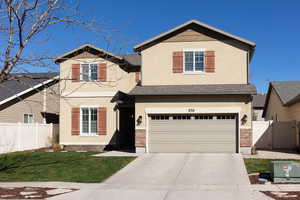 View of front of property with stone siding, driveway, stucco siding, an attached garage, and roof with shingles