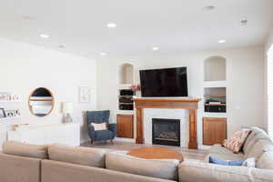 Living room featuring built in shelves, wood finished floors, a fireplace, and recessed lighting