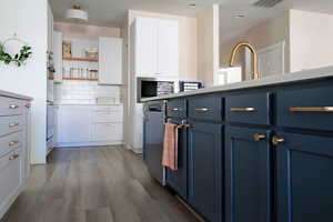 Two tone kitchen featuring two tone color scheme, dark wood-style floors, open shelves, tasteful backsplash, and stainless steel appliances