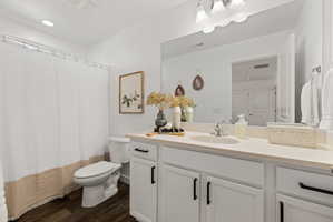 Full bathroom with vanity, curtained shower, and dark wood finished floors