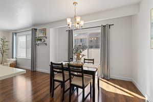 Dining room with dark wood-style floors and suspended lighting