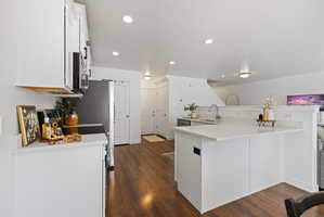 Kitchen with white cabinets, electric stove, dark wood-style flooring, a textured ceiling, and recessed lighting