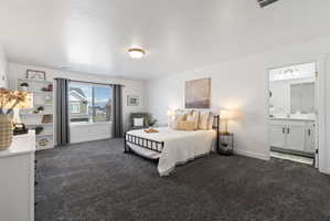 Bedroom featuring dark colored carpet, a textured ceiling, and ensuite bath