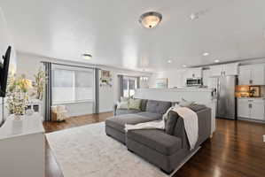 Living area with dark wood-style flooring, plenty of natural light, a textured ceiling, and a chandelier