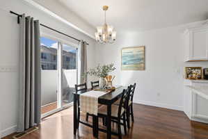 Dining area featuring suspended lighting and dark wood-style flooring