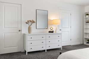 Bedroom with dark carpet and baseboards