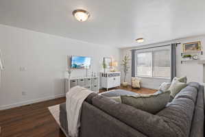 Living area featuring dark wood finished floors and a textured ceiling