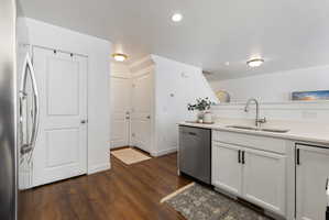 Kitchen with stainless steel appliances, white cabinets, light stone counters, dark wood-style flooring, and a textured ceiling