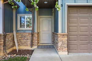 Entrance to property with stone siding and a garage