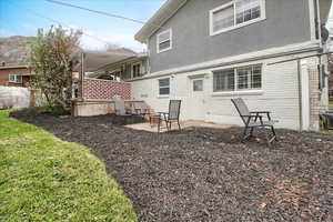 Back of house with a patio, brick siding, stucco siding, and walkout basement