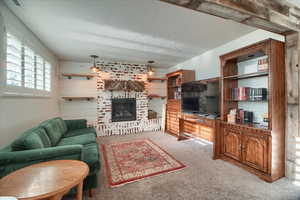 Living room with light carpet, a textured ceiling, and a brick fireplace