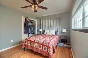 Bedroom with light wood finished floors, a ceiling fan, and a closet