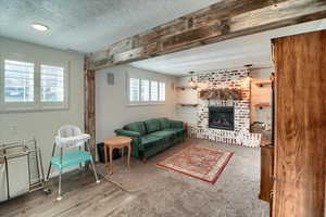 Living room with a brick fireplace, a textured ceiling, and light carpet