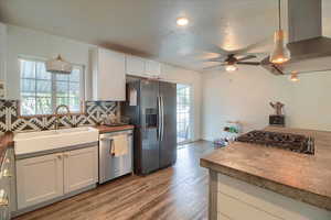 Kitchen with pendant lighting, island exhaust hood, backsplash, and stainless steel appliances