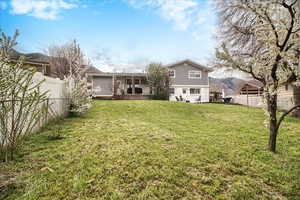 Rear view of property with a fenced backyard, deck, and stucco siding