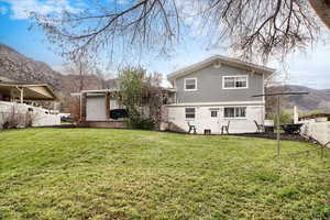 Rear view of house featuring a lawn, stucco siding, brick siding, and a deck with mountain view