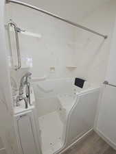 Full bathroom featuring dark wood finished floors, walk in tub