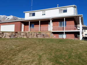 View of front facade with brick siding, a mountain view, a front lawn, and a garage