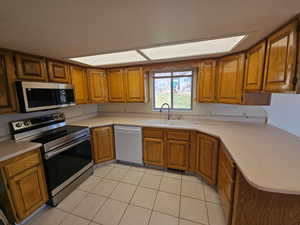 Kitchen with stainless steel appliances, wood finish cabinetry, and light countertops