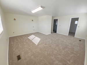 Primary bedroom with baseboards and light carpet, private bathroom and walk in closet