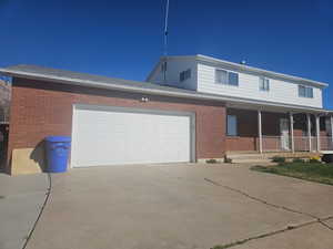 View of front of house featuring a porch, driveway, brick siding, an attached garage, and roof with shingles