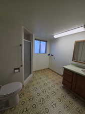 Bathroom with a stall shower, vanity, light flooring and laundry area