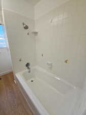 Bathroom featuring wood finished floors and bathing tub / shower combination
