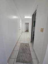 Hallway featuring light tile patterned floors and baseboards
