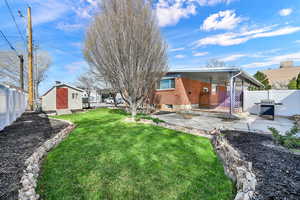 Rear view of house with a fenced backyard, brick siding, a patio, and a storage unit