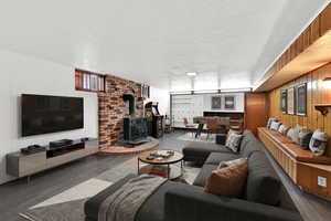 Living room featuring wood walls, wood finished floors, a wood stove, and a textured ceiling