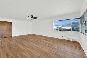 Unfurnished bedroom featuring a textured ceiling, light wood-style floors, a ceiling fan, and a closet
