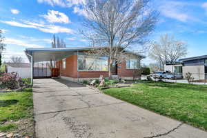 View of front facade with driveway, brick siding, and an attached carport