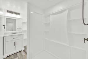 Full bath featuring a stall shower, vanity, and light wood finished floors