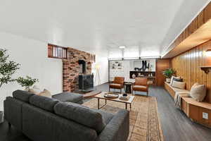 Living area with wood walls, dark wood-style flooring, a wood stove, and a textured ceiling