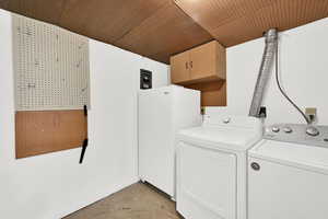 Laundry room featuring washing machine and dryer, unfinished concrete flooring, and cabinet space