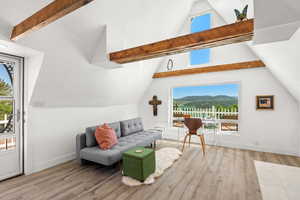 Additional living space featuring light wood finished floors, lofted ceiling, healthy amount of natural light, and a mountain view