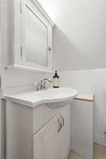 Half bathroom with vanity and vaulted ceiling