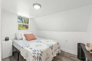 Bedroom with dark wood finished floors and lofted ceiling