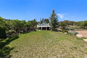 View of green lawn featuring view of wooded area