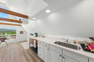 Bar featuring white cabinetry, light wood-style flooring, vaulted ceiling with beams, light stone counters, and recessed lighting