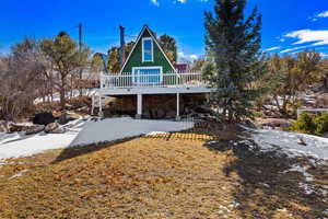 Snow covered property with a wooden deck and stone siding
