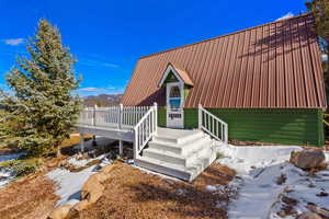 View of front of home with a deck with mountain view and a metal roof