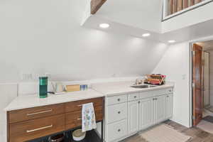 Bar area with recessed lighting, lofted ceiling, light wood-type flooring, and white cabinets