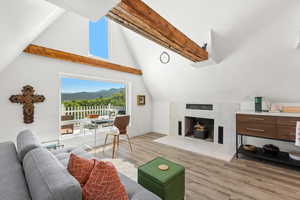 Living room with light wood-style flooring, a fireplace, a mountain view, and lofted ceiling