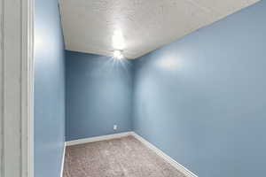 Empty room featuring a textured ceiling and light carpet