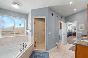 Ensuite bathroom featuring double vanity, a tub with jets, a shower stall, and vaulted ceiling